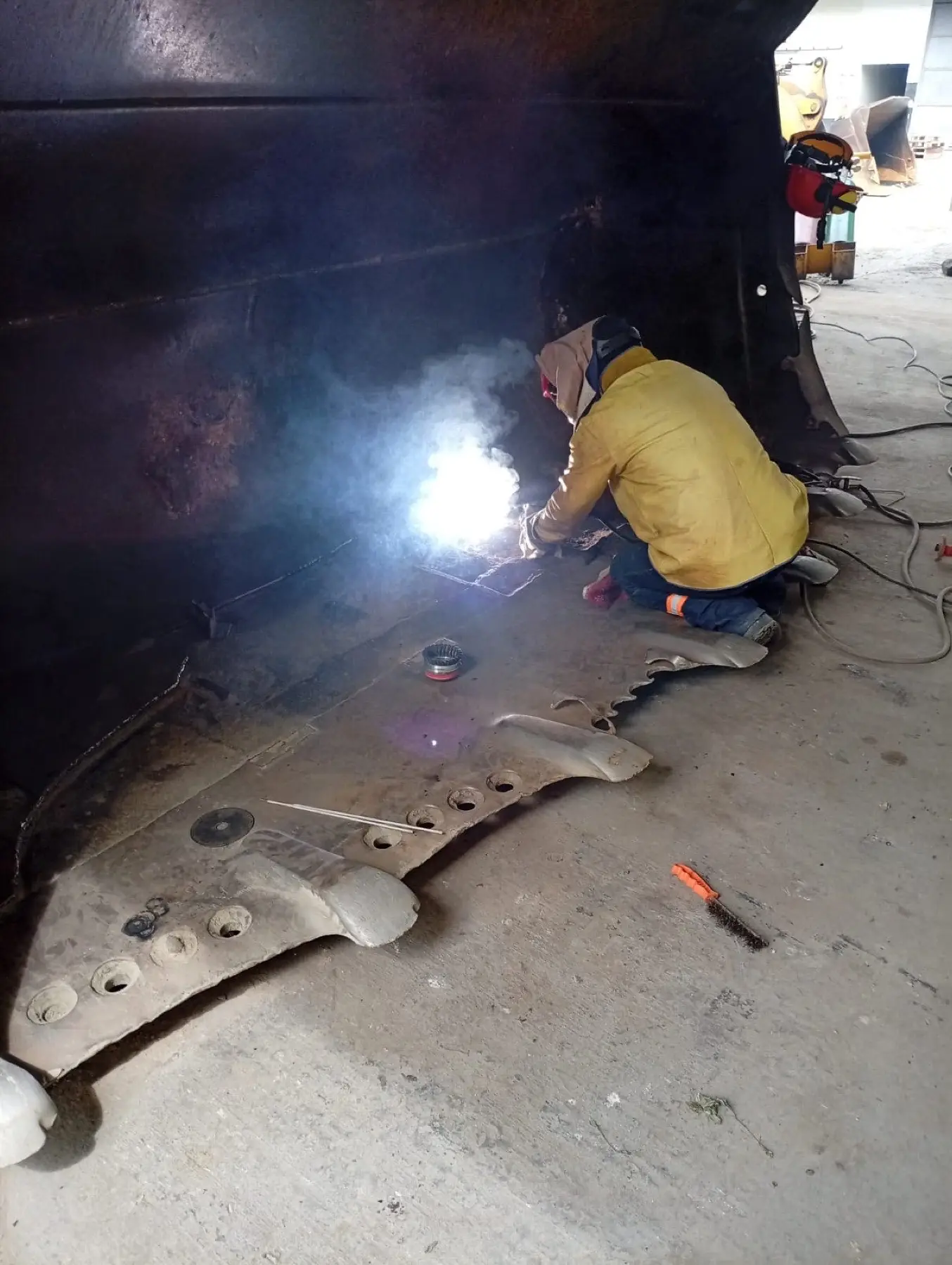 Soldador de SIMA ejecutando reparación estructural dentro de un balde de cargador