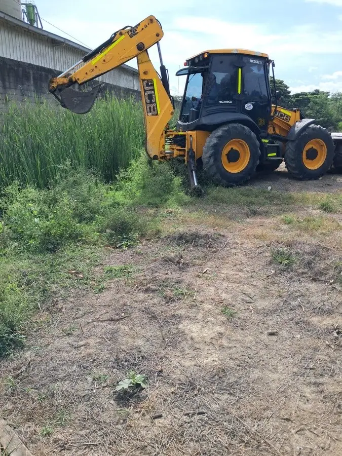 Retroexcavadora trabajando en el mantenimiento de un canal perimetral en zona verde industrial